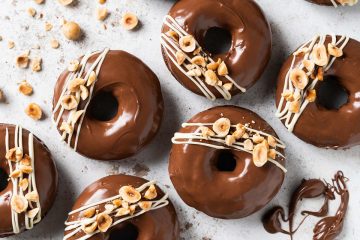 My Nutella donuts are so good, you will want to inhale more than one! A light Nutella chocolate cake baked donut is topped with smooth and glossy Nutella spread and decorated with a white chocolate drizzle and chopped toasted hazelnuts. Chocolate hazelnut heaven! Recipe by movers and bakers