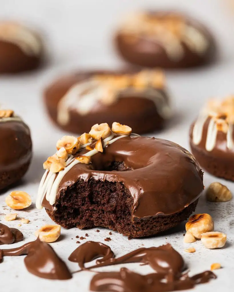 My Nutella donuts are so good, you will want to inhale more than one! A light Nutella chocolate cake baked donut is topped with smooth and glossy Nutella spread and decorated with a white chocolate drizzle and chopped toasted hazelnuts. Chocolate hazelnut heaven! Recipe by movers and bakers