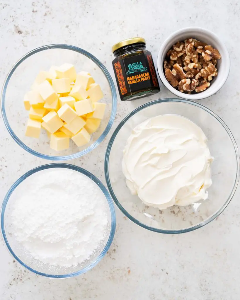 Ingredients for the icing: unsalted butter, icing sugar, vanilla, cream cheese and walnuts (plus carrot ribbons for decoration). Recipe by movers and bakers