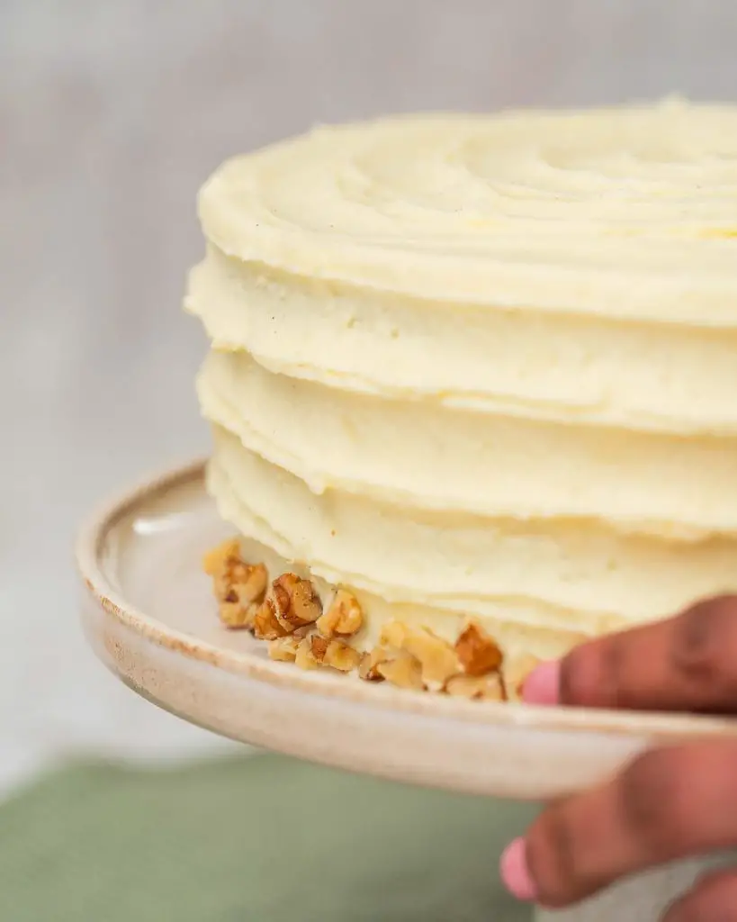 Gently pressing some chopped nuts along the base of the iced cake...