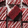 My red velvet brownies are fudgy and chewy, with a perfectly balance flavour, and topped with a scrumptious cream cheese drizzle. Recipe by movers and bakers