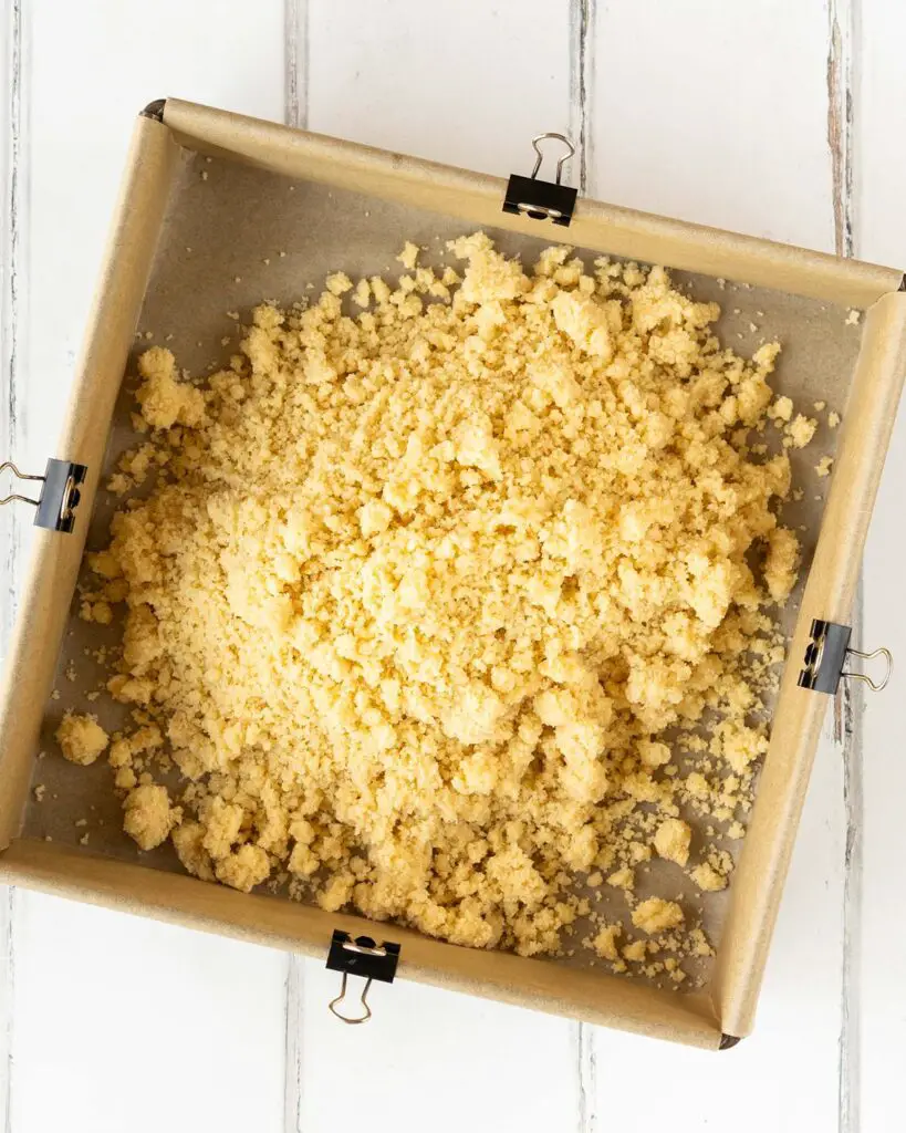 Tip the shortbread crumbs into the prepared tin before pressing down...