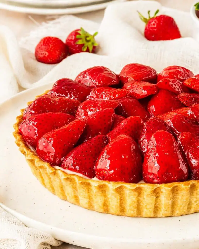 My strawberry tart recipe is hugely inspired by the glorious French strawberry tart we enjoy during out holidays! Buttery shortcrust pastry, smooth creme patisserie and beautifully glazed fresh strawberries make this a summertime treat! Recipe by movers and bakers