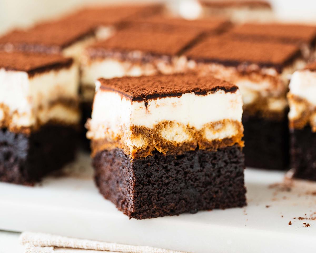 Tiramisu brownies. Putting together two of my all time favourite desserts to make one epic mash-up! Fudgy brownie, coffee laced sponge fingers and silky mascarpone cream all topped with a generous dusting of cocoa. Utterly heavenly! Recipe by movers and bakers
