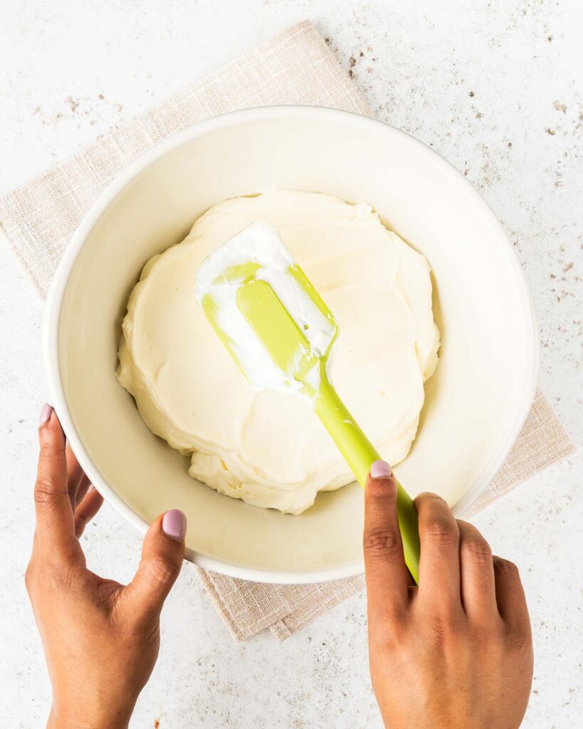 Folding ingredients together for the mascarpone topping. Recipe by movers and bakers