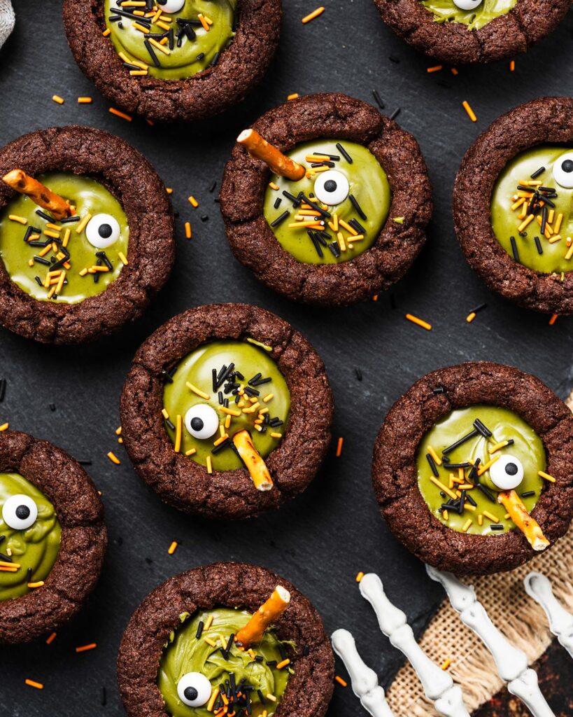 My witches’ cauldron cookie cups are chewy chocolate cookies filled with a delicious “potion” and sprinkles. A fun Halloween for everyone! Recipe by movers and bakers