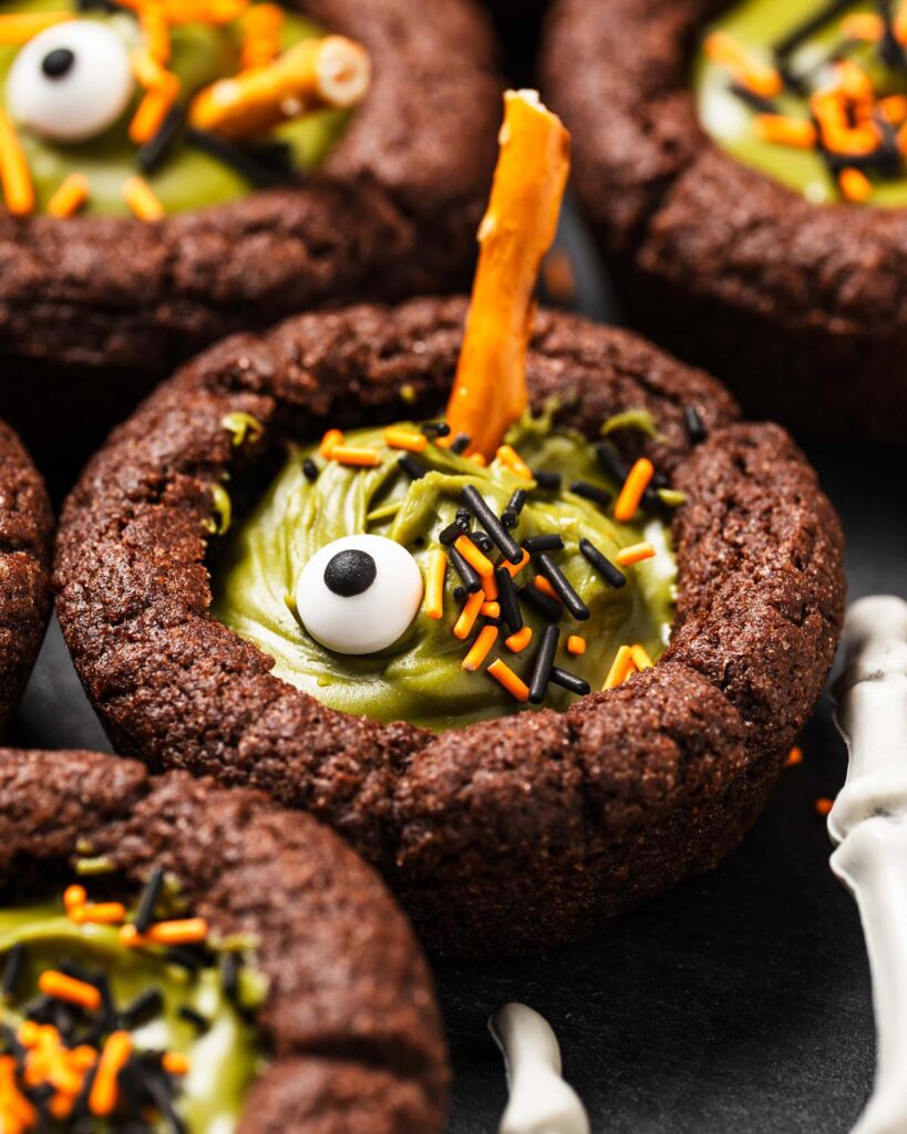 My witches’ cauldron cookie cups are chewy chocolate cookies filled with a delicious “potion” and sprinkles. A fun Halloween for everyone! Recipe by movers and bakers