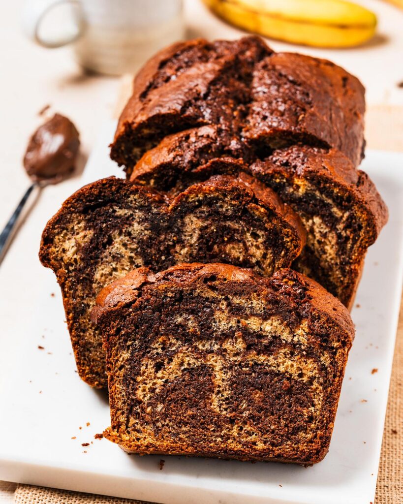Elevate the classic banana bread with Nutella delectable twist on a classic! Nutella banana bread is the perfect homely bake for any time! Recipe by movers and bakers