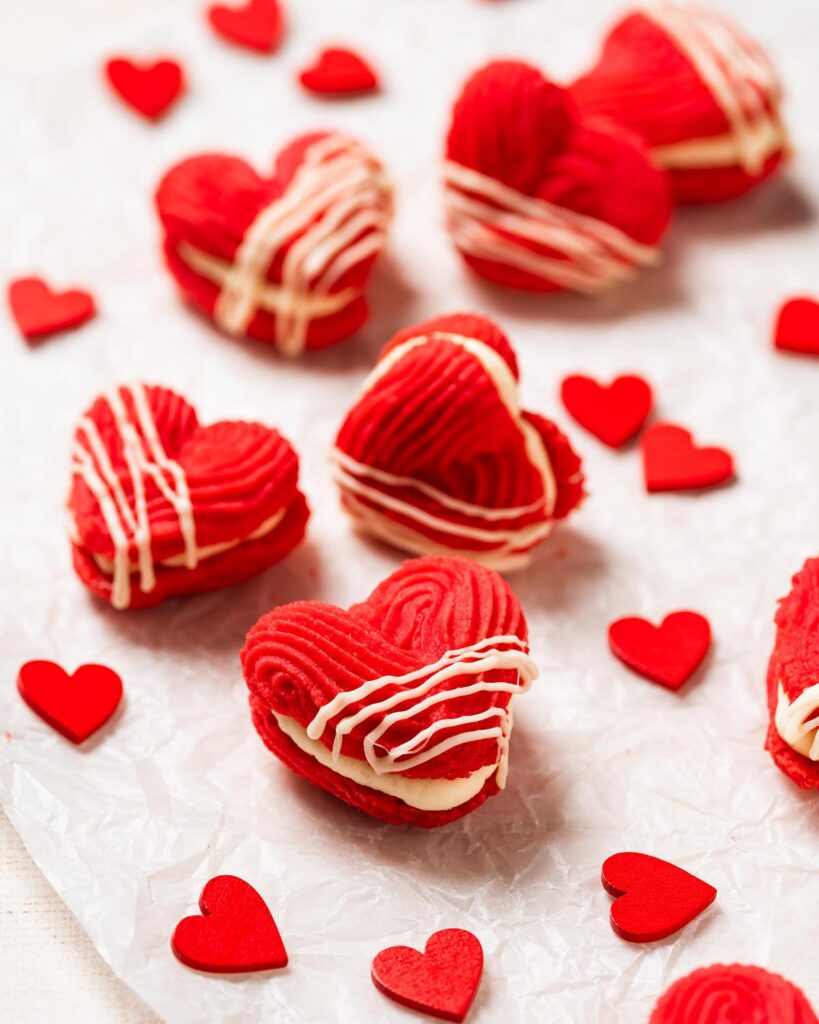My Valentine's Viennese hearts are buttery, rich and utterly irresistible! Vibrant red piped shortbread biscuits filled with an airy whipped white chocolate ganache make these beauties perfect for Valentine's, Galentine's or any time! Recipe by movers and bakers
