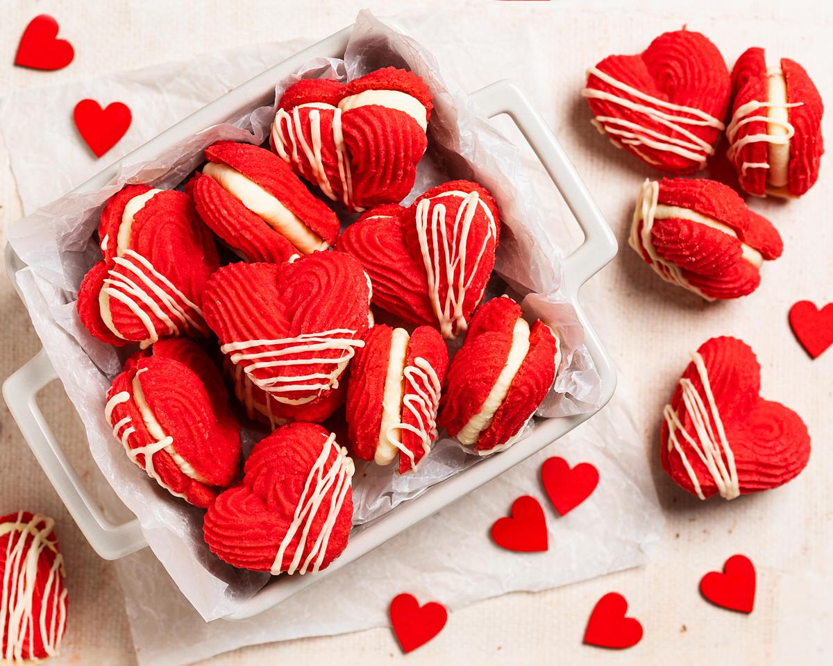 My Valentine's Viennese hearts are buttery, rich and utterly irresistible! Vibrant red piped shortbread biscuits filled with an airy whipped white chocolate ganache make these beauties perfect for Valentine's, Galentine's or any time! Recipe by movers and bakers