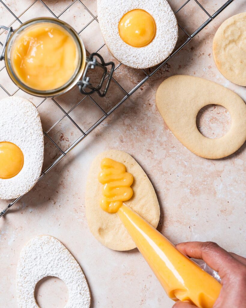 Piping the lemon curd onto a base cookie...