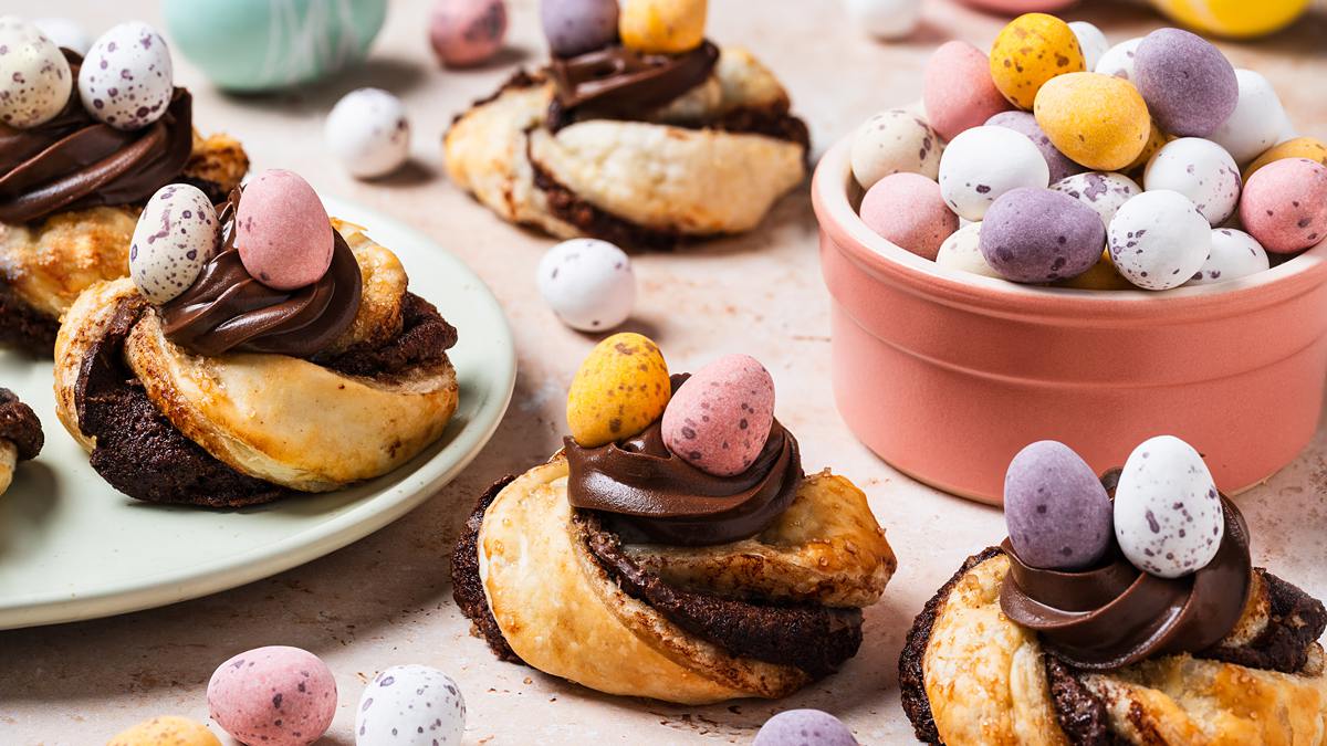 Golden, flakey, Nutella-filled pastry twists, curled into nests and topped with more Nutella and mini eggs, these puff pastry Easter nests are everyone's favourite! Recipe by movers and bakers
