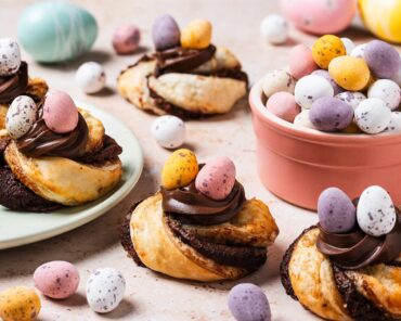 Golden, flakey, Nutella-filled pastry twists, curled into nests and topped with more Nutella and mini eggs, these puff pastry Easter nests are everyone's favourite! Recipe by movers and bakers