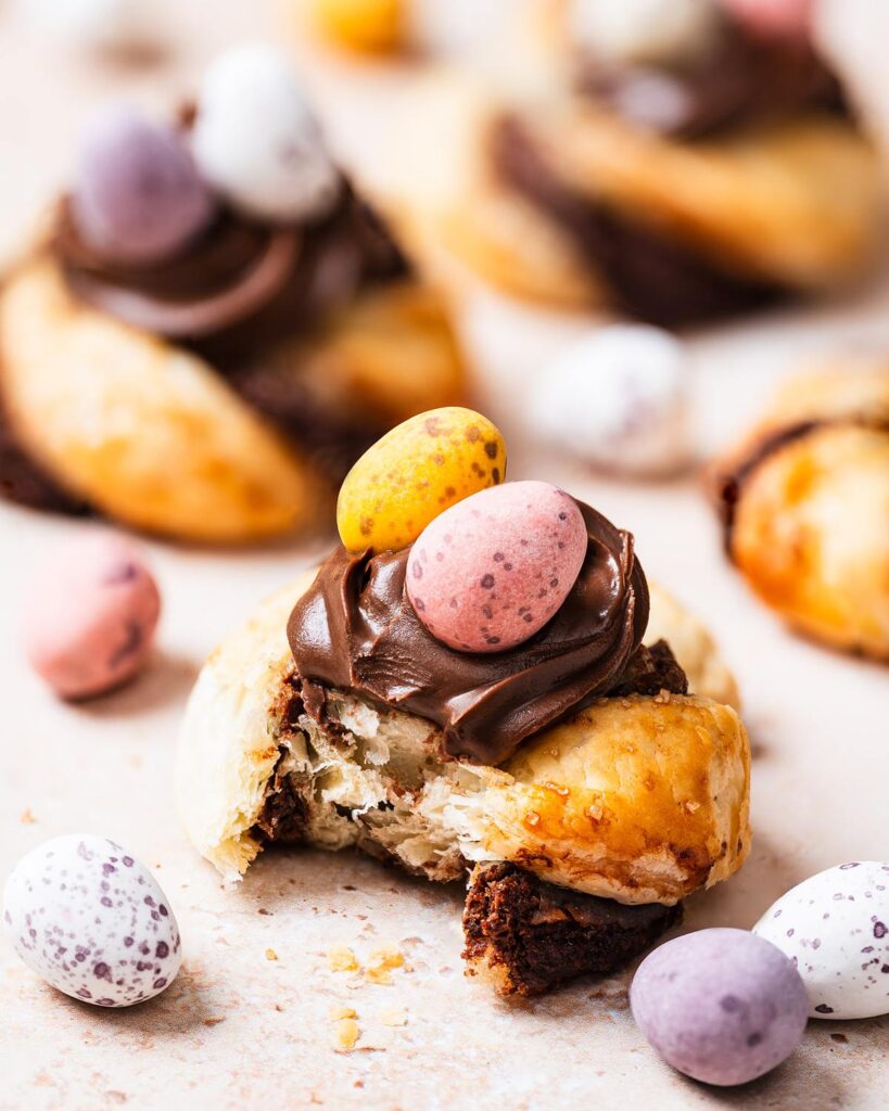 Golden, flakey, Nutella-filled pastry twists, curled into nests and topped with more Nutella and mini eggs, these puff pastry Easter nests are everyone's favourite! Recipe by movers and bakers