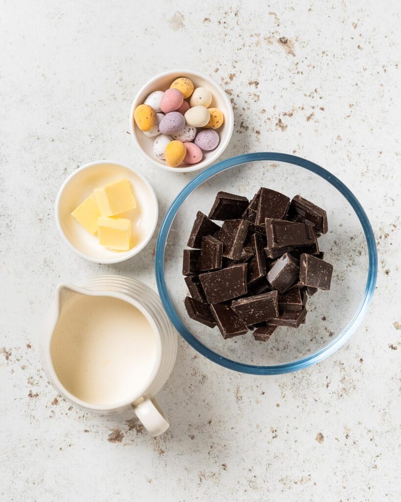 Ingredients for the ganache and topping: dark chocolate, double (heavy) cream, unsalted butter and mini eggs. Recipe by movers and bakers