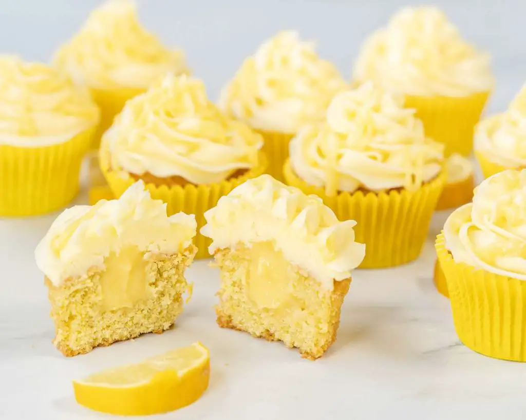 Lemon cupcakes with cut open cupcake showing the lemon curd filling in the middle