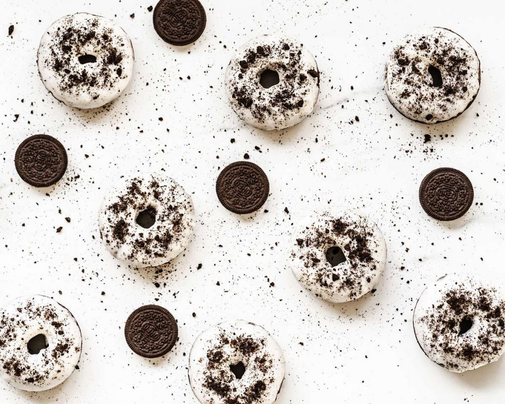 Delicious cakey, chocolatey donuts are light and delicious, topped with a yummy tangy cream cheese glaze and plenty of Oreos! Recipe by movers and bakers