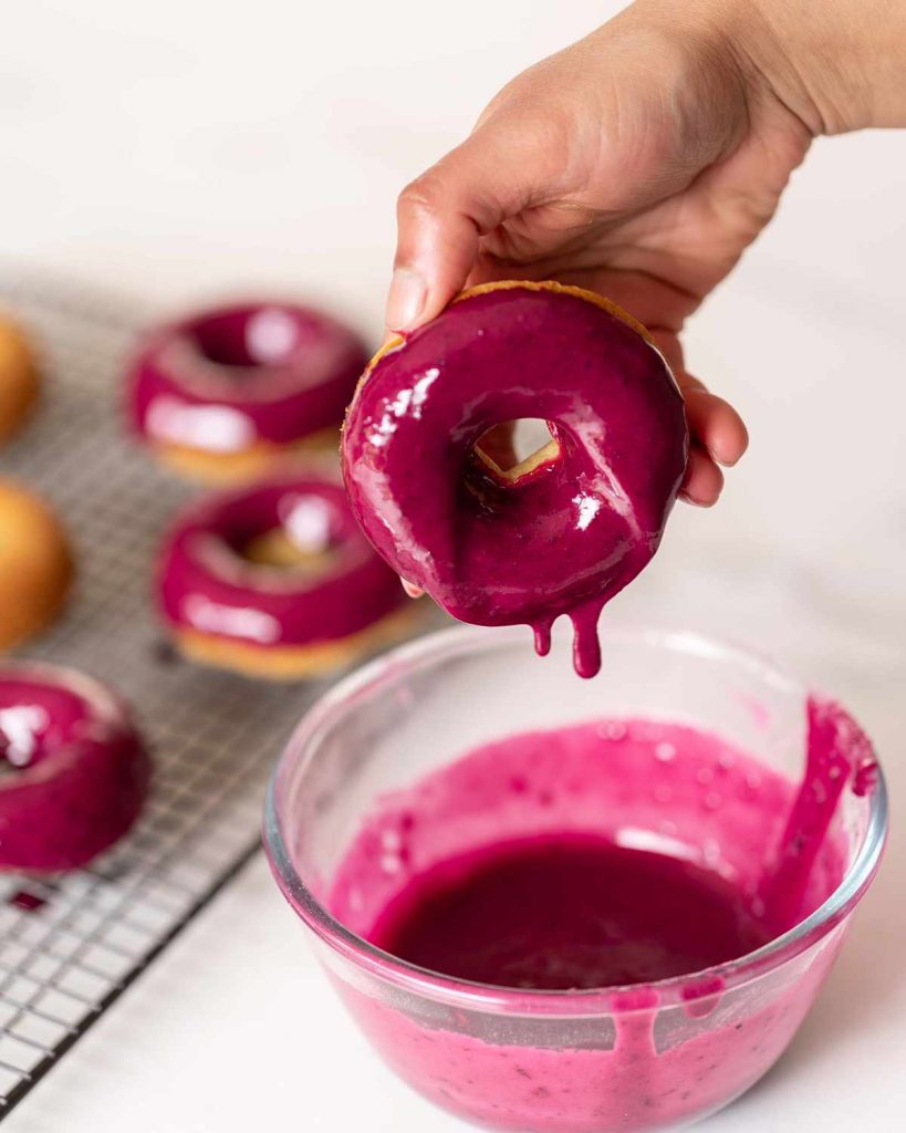 Dipping lemon blueberry donuts in the blueberry glaze.