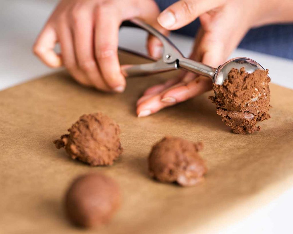Laying brownie cookie scoops on a tray before baking