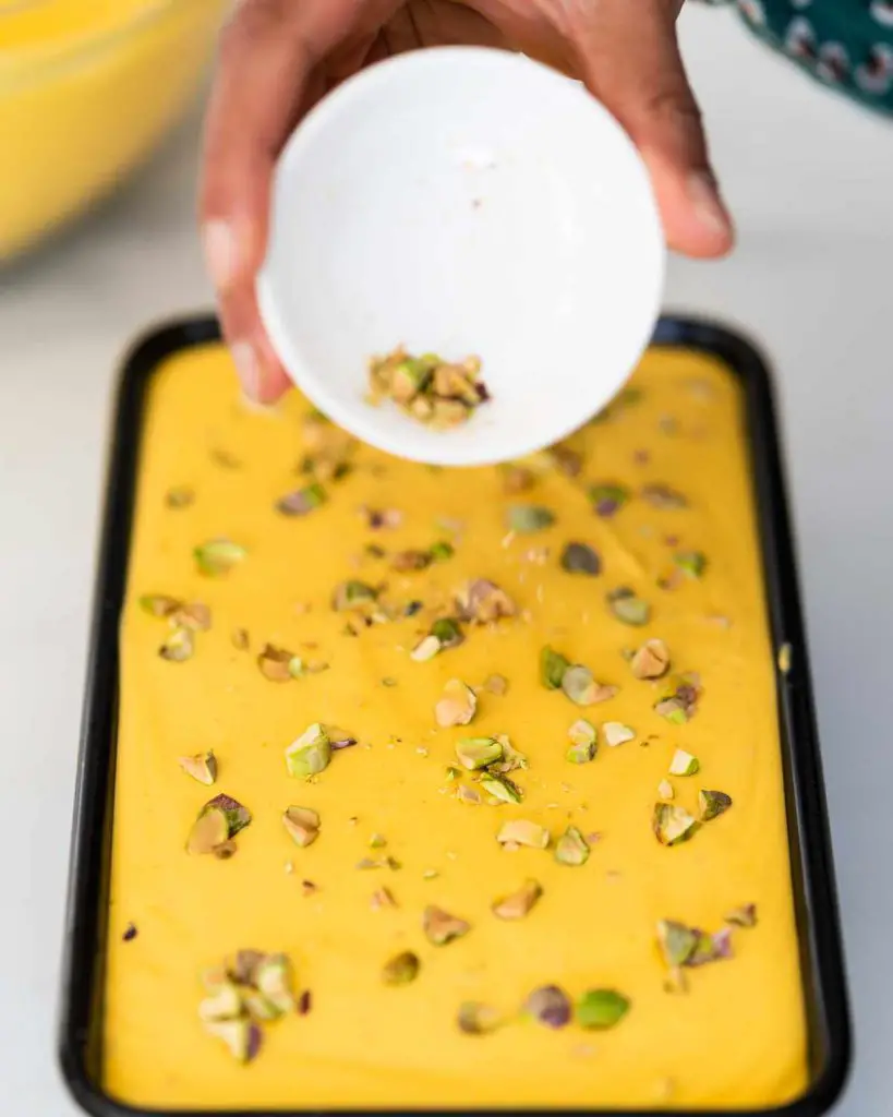 Sprinkling pistachios over the top of the mango ice cream. Recipe by movers and bakers