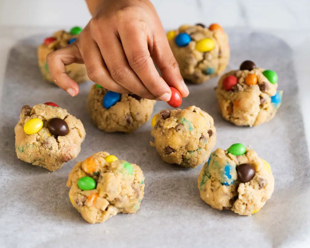 The cookie dough balls are studded with extra M&Ms before being chilled and then baked. Recipe by movers and bakers