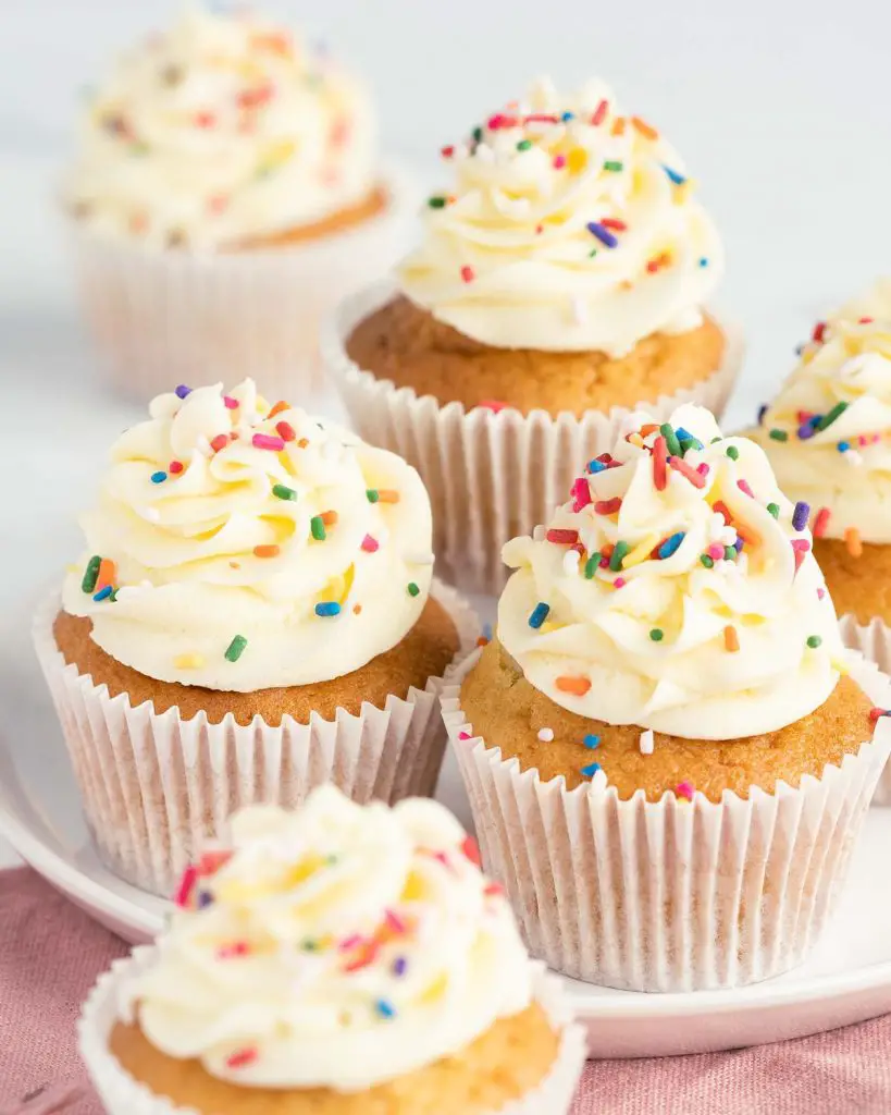 A selection of moist vanilla cupcakes with vanilla buttercream swirl.