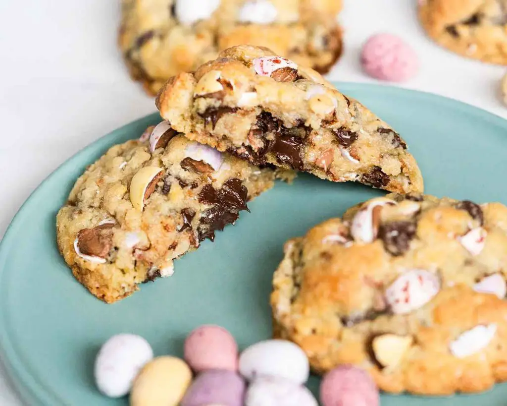 A splite Mini Egg chocolate chip cookie showing gorgeous gooey chocolate chips in the middle. Inspired by chunky NYC style cookies, recipe by movers and bakers