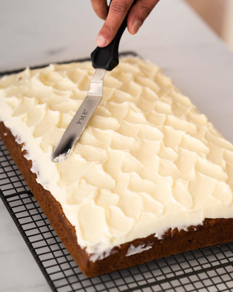 Use an off set spatula to texture up your icing before topping with walnuts. Recipe by movers and bakers