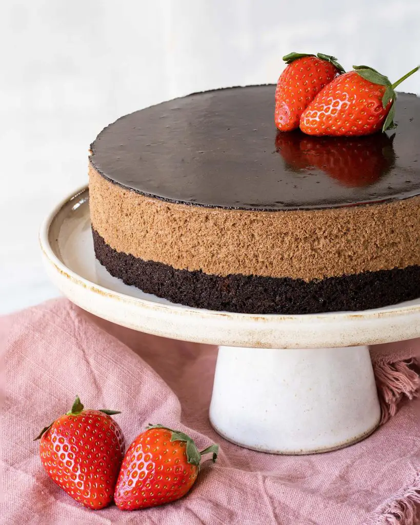 My brownie mousse cake has a beautiful soft brownie layer, a generous light and richly chocolatey mousse layer and a smooth shiny cocoa glaze. A perfect celebration cake for any occasion! Recipe by movers and bakers