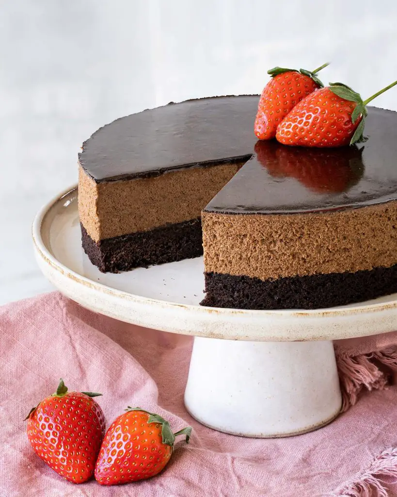 My brownie mousse cake has a beautiful soft brownie layer, a generous light and richly chocolatey mousse layer and a smooth shiny cocoa glaze. A perfect celebration cake for any occasion! Recipe by movers and bakers