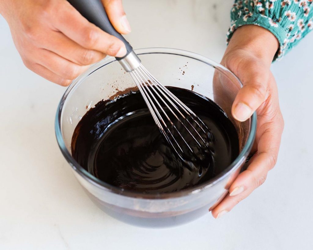 Mixing the melted butter and cocoa powder together into a smooth glossy chocolatey delight! Recipe by movers and bakers