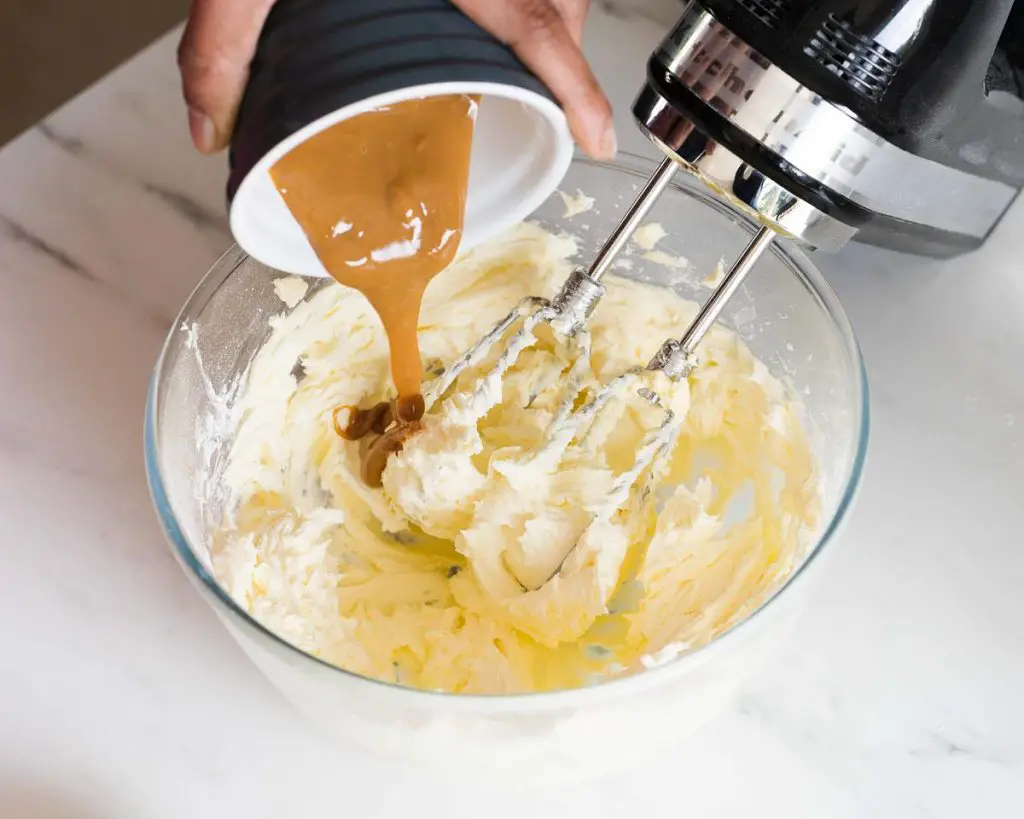 Adding caramel to make the caramel buttercream before beating until light and fluffy. Yum! Recipe by movers and bakers