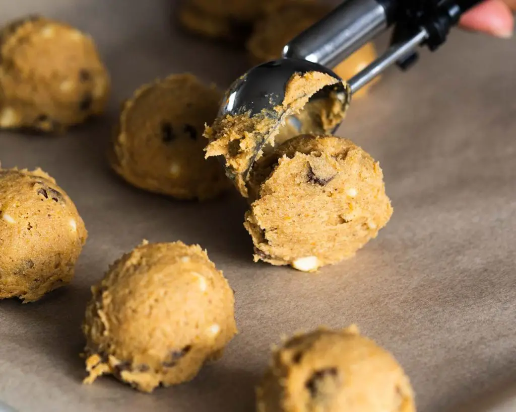 Scooping the cookie dough onto a baking tray before chilling to firm up. Recipe by movers and bakers
