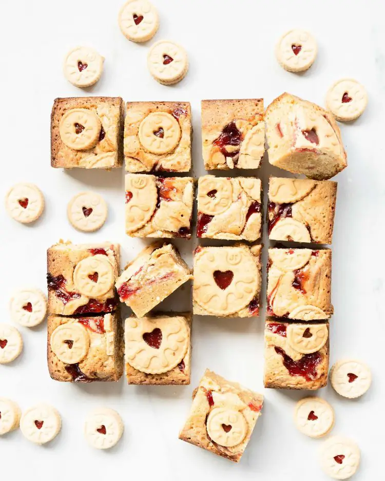 Jammie dodger blondies. Yummy fudgy white chocolate blondies packed with beautiful jammie dodger biscuits and swirls of smooth raspberry jam. Recipe by movers and bakers