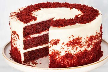 The best eggless red velvet cake recipe. Delicious light chocolate and vanilla flavoured cake layers filled and covered with a beautiful rich cream cheese icing then decorated with red velvet cake crumbs. Recipe by movers and bakers