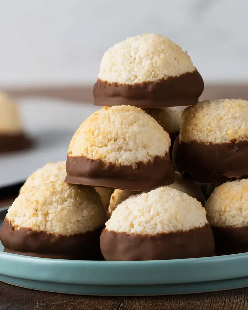 Coconut chocolate macaroons. These eggless macaroons use only three ingredients to make the most delicious macaroon cookies. These coconut cookies are crispy on the outside, wonderfully chewy in the middle and dipped in smooth milk chocolate. Just heavenly! Recipe by movers and bakers