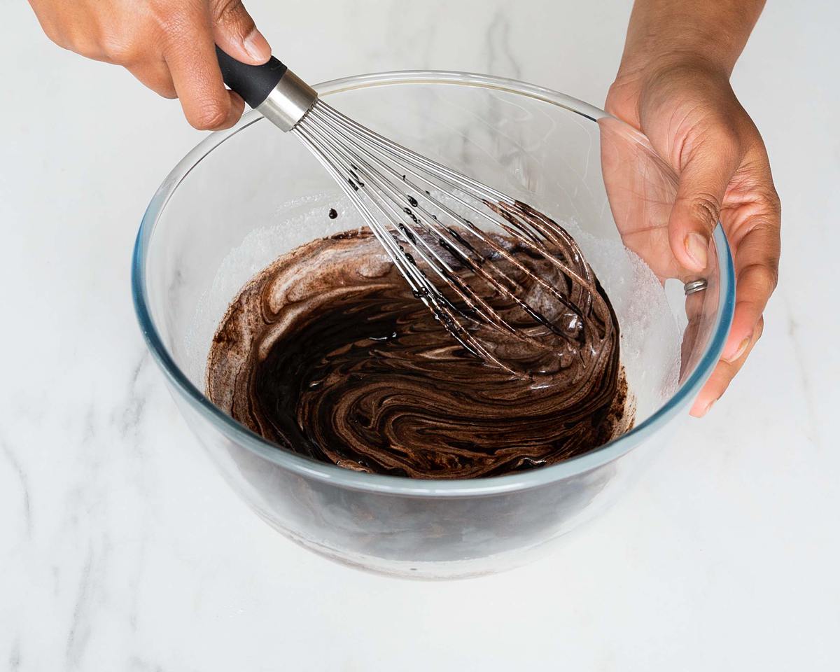 Adding the chocolate mixture and whisking it all together. Recipe by movers and bakers