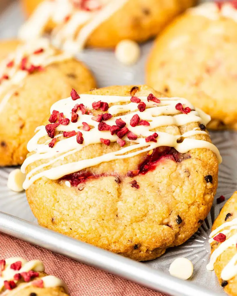 My wonderfully soft and chewy raspberry and white chocolate cookies are packed with lots of delicious pops of flavour, and topped with an extra pretty drizzle of white chocolate and freeze dried raspberries! Recipe by movers and bakers